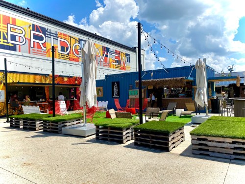 A vibrant outdoor space with colorful murals, seating areas, and decorative lights, inviting people to relax and socialize.