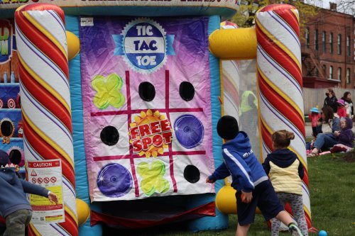 Children playing tic-tac-toe on a colorful inflatable game at an outdoor event.