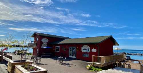 A red seafood market building by the water, with outdoor seating and a clear blue sky in the background.