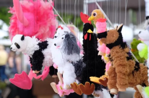 Colorful plush animal puppets hanging on strings, including a panda, chicken, and various other animals.