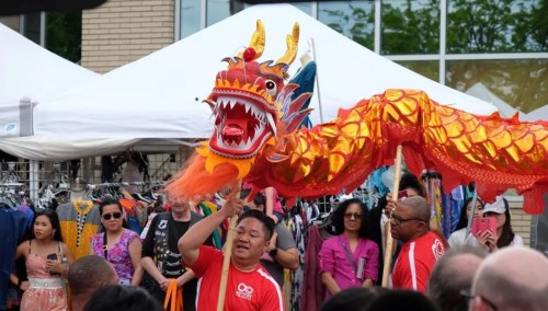 A vibrant dragon dance performance at a festival, with performers and onlookers in a lively outdoor setting.