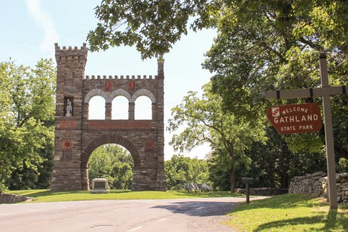 A stone archway with three arches and a statue, next to a sign welcoming visitors to Gathland State Park.