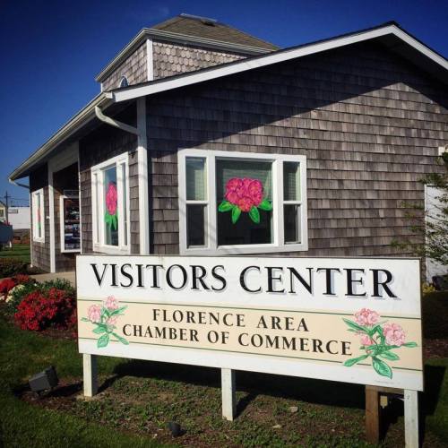 A charming visitors center with a sign for the Florence Area Chamber of Commerce, featuring floral decorations.