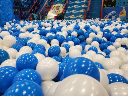 A colorful ball pit filled with blue and white balls, with a playful atmosphere in a recreational space.