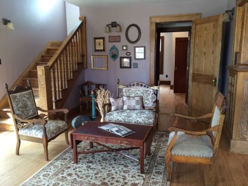 Cozy living room with vintage furniture, a wooden staircase, and decorative wall art in soft purple tones.