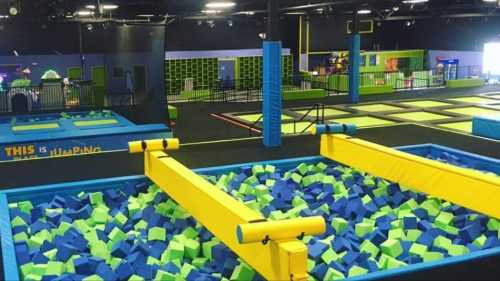 A vibrant indoor trampoline park featuring foam pits, trampolines, and colorful play areas.