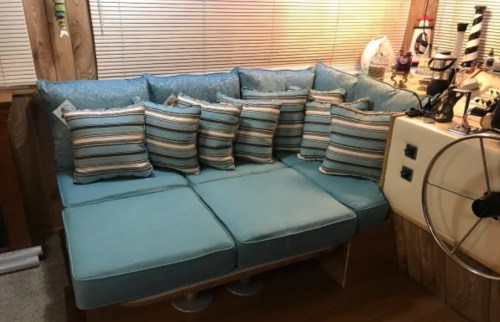 A cozy turquoise sectional sofa with striped pillows, set in a warmly lit room with wooden accents.