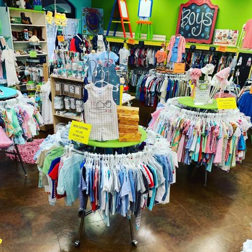 A colorful children's clothing store with racks of boys' clothes and displays on circular tables.