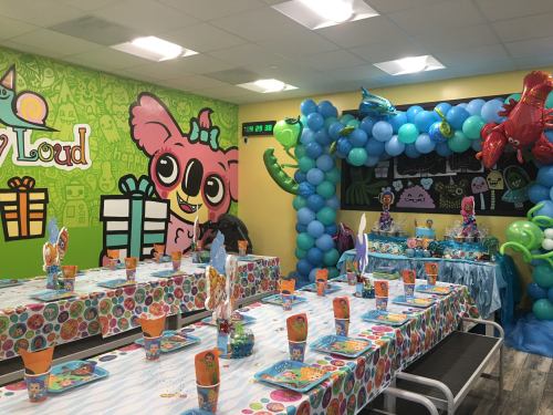 Colorful party room decorated with balloons, themed table settings, and vibrant wall art for a festive celebration.