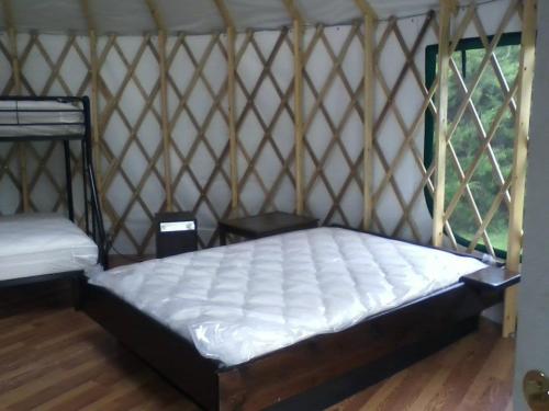 Interior of a yurt featuring a double bed, bunk beds, and wooden furniture against a lattice wall.