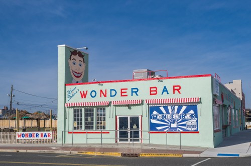 A colorful building with "Wonder Bar" signage and a smiling cartoon face on the side, set against a clear blue sky.