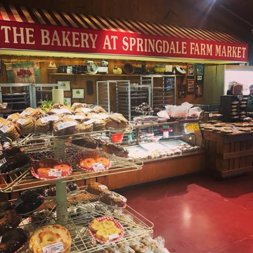 A bakery display at Springdale Farm Market featuring various baked goods and pastries on shelves and a stand.