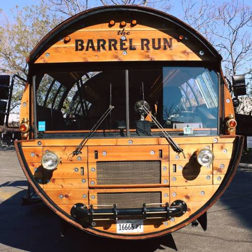 A vintage-style wooden bus with "The Barrel Run" sign on the front, featuring large windows and a round design.