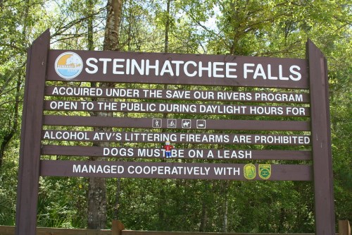 Sign at Steinhatchee Falls detailing park rules, including hours, prohibited items, and dog leash requirements.