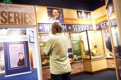 A person stands in a museum exhibit, looking at displays featuring historical figures and memorabilia.