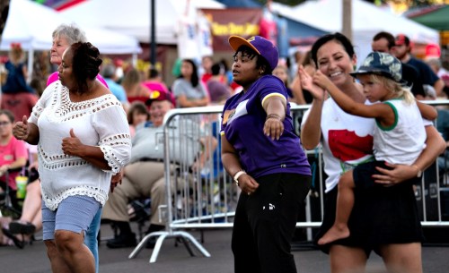 A lively outdoor scene with people dancing, enjoying music, and celebrating at a community event.