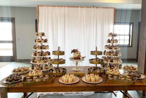A beautifully arranged dessert table featuring cupcakes, a cake, and assorted treats on elegant stands.