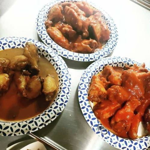 Three plates of chicken wings in different sauces, arranged on patterned paper plates.