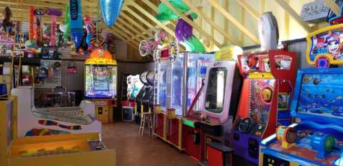 A colorful arcade filled with various games and machines, including claw machines and racing games, under a bright ceiling.