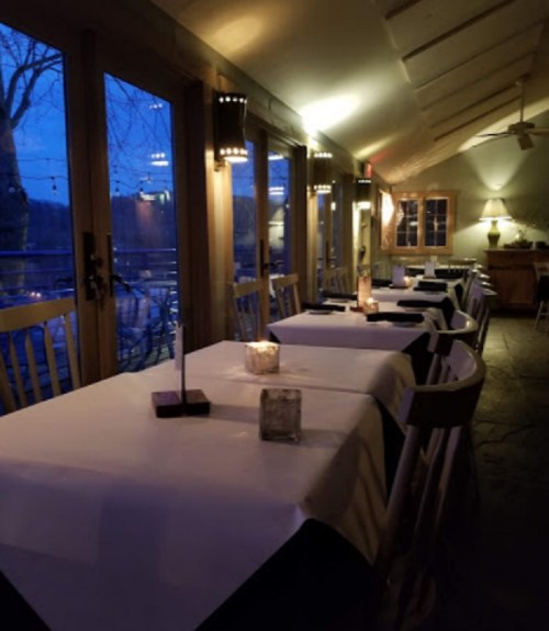 Cozy restaurant interior at dusk, featuring tables with white tablecloths and soft candlelight.