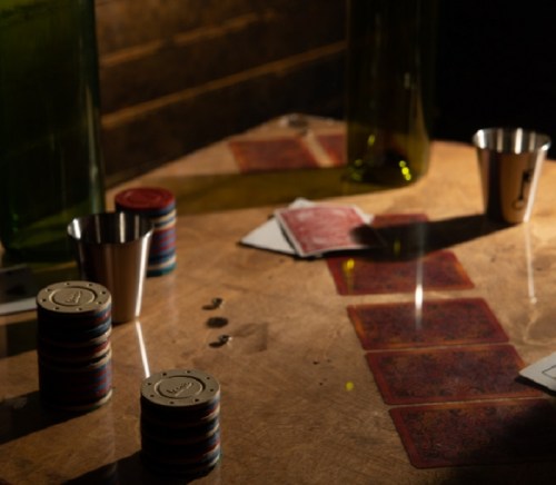 A dimly lit table with poker chips, playing cards, and metal cups, creating a casino atmosphere.