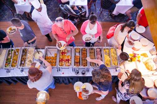 Aerial view of a buffet with people serving themselves food at a restaurant, with tables set in the background.