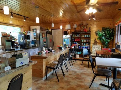 Cozy café interior with wooden walls, tables, chairs, and a counter displaying coffee machines and colorful dishware.