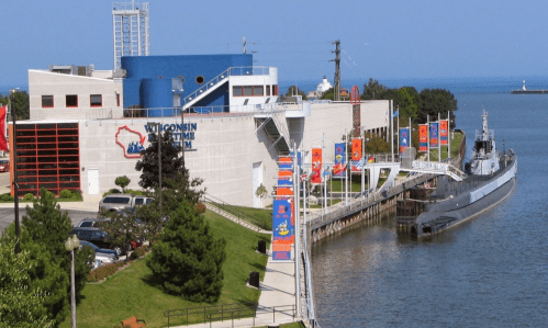 Exterior view of the Wisconsin Maritime Museum, featuring a docked submarine and colorful banners along the waterfront.
