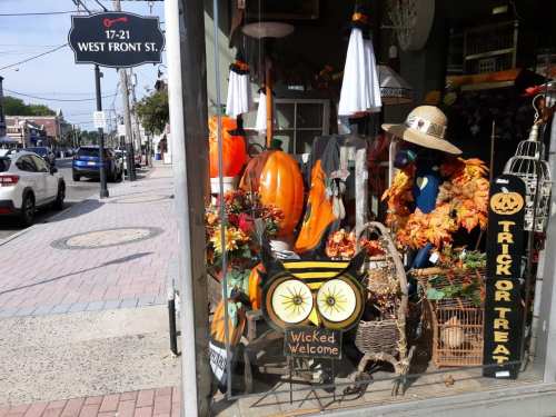A storefront decorated for Halloween with pumpkins, autumn leaves, and a "Wicked Welcome" sign.
