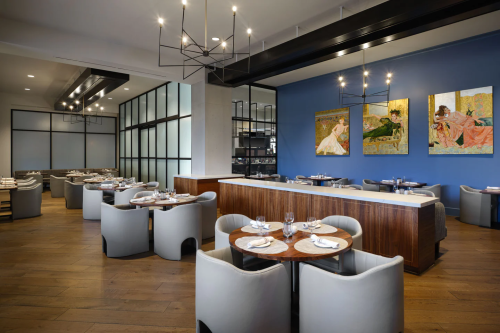 Modern restaurant interior featuring elegant seating, wooden tables, and colorful artwork on the walls.