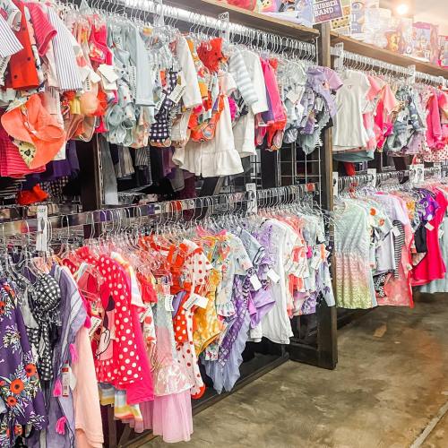A colorful display of children's clothing hanging on racks in a store, featuring various patterns and styles.