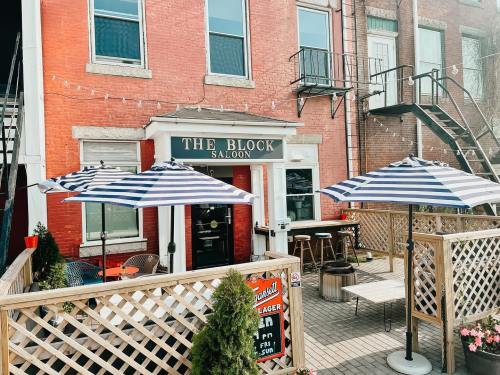 Exterior of The Block Saloon with striped umbrellas, outdoor seating, and a rustic brick building.