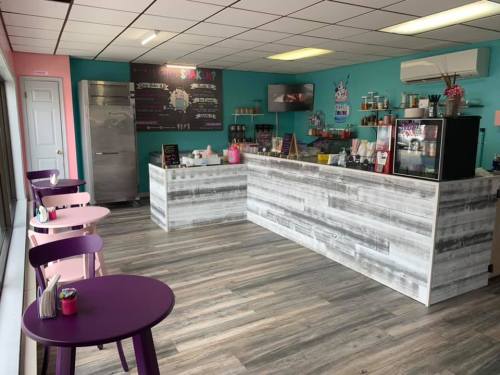 Brightly colored café interior with a wooden counter, seating area, and a menu board on the wall.