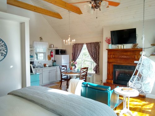 Cozy interior of a cabin with a kitchen, dining area, fireplace, and large windows letting in natural light.
