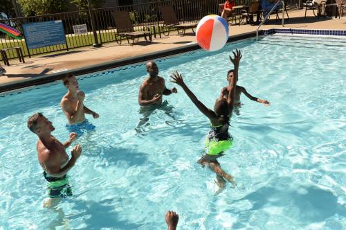 A group of people playing with a beach ball in a swimming pool on a sunny day.