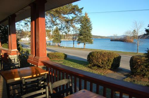 View from a porch overlooking a calm lake, with trees and a road in the foreground on a sunny day.