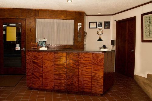Wooden reception desk in a cozy, warmly lit lobby with framed pictures and a window.
