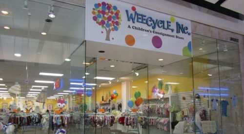 Entrance of Weecycle Inc., a children's consignment store, featuring colorful decor and clothing displays.