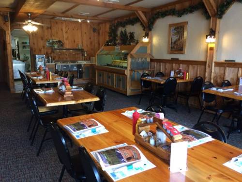 Cozy restaurant interior with wooden decor, tables set for dining, and a buffet area in the background.
