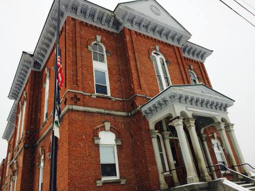 Historic brick building with columns, flags, and snow, showcasing classic architectural details.