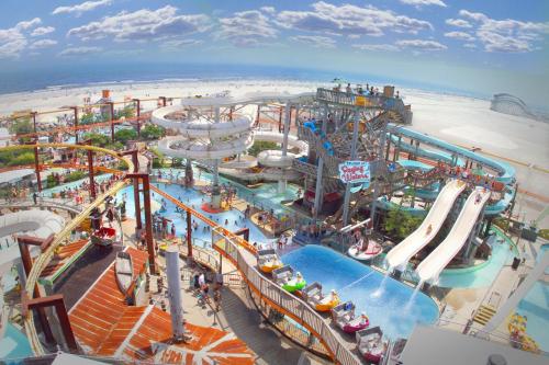 A vibrant water park with slides, pools, and families enjoying a sunny day by the beach.