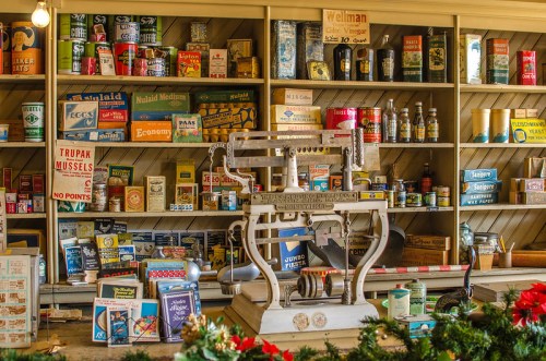 A vintage store display featuring an old-fashioned scale and shelves filled with colorful canned goods and products.