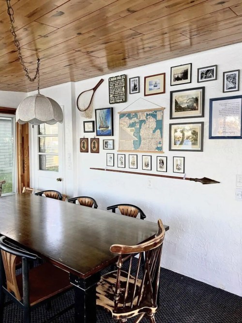 A cozy dining area featuring a wooden table, chairs, and a gallery wall of framed art and photographs.