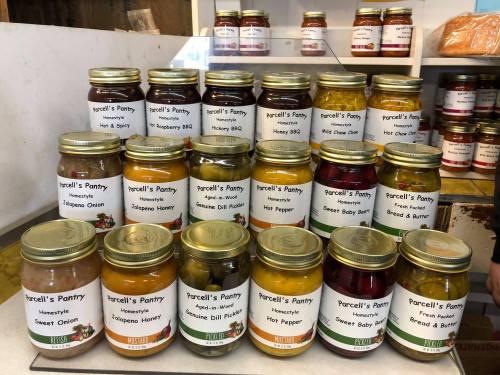 A display of jars labeled with various condiments and sauces, including honey, hot pepper, and sweet onion.
