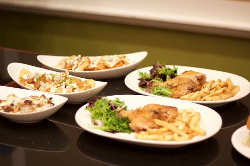 Plates of food featuring fried chicken, fries, salads, and a dish of pasta, arranged on a table.