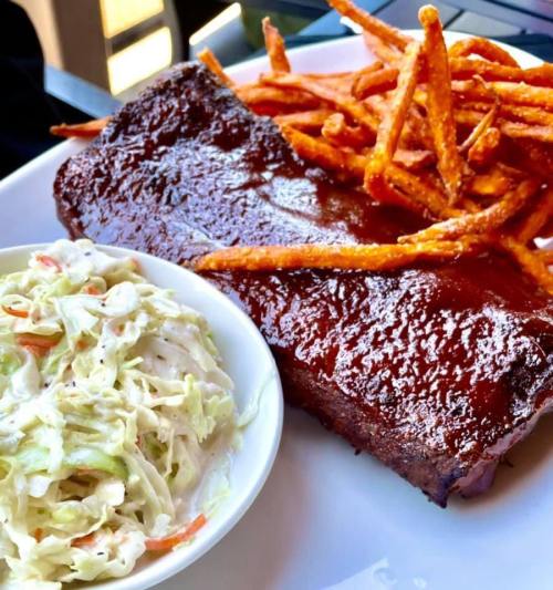 A plate featuring a barbecue rib, sweet potato fries, and a side of coleslaw.