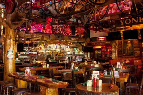 A rustic bar interior with wooden tables, a vibrant bar, and Western-themed decor, including wagon wheels and taxidermy.