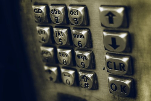 Close-up of a metallic elevator keypad with numbers and buttons for clear, OK, and directional arrows.