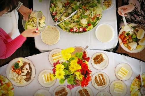 A top-down view of a festive table with salads, entrees, and colorful flower arrangements.