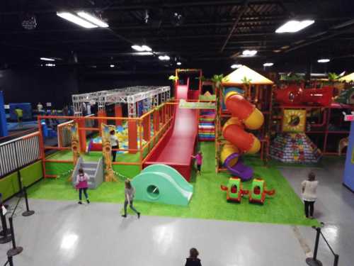 A colorful indoor play area with slides, climbing structures, and play equipment for children.